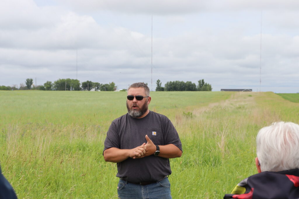 Man talking to group outside in grassy field